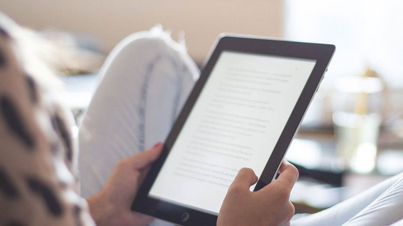 En person leser på en Kindle på sofaen