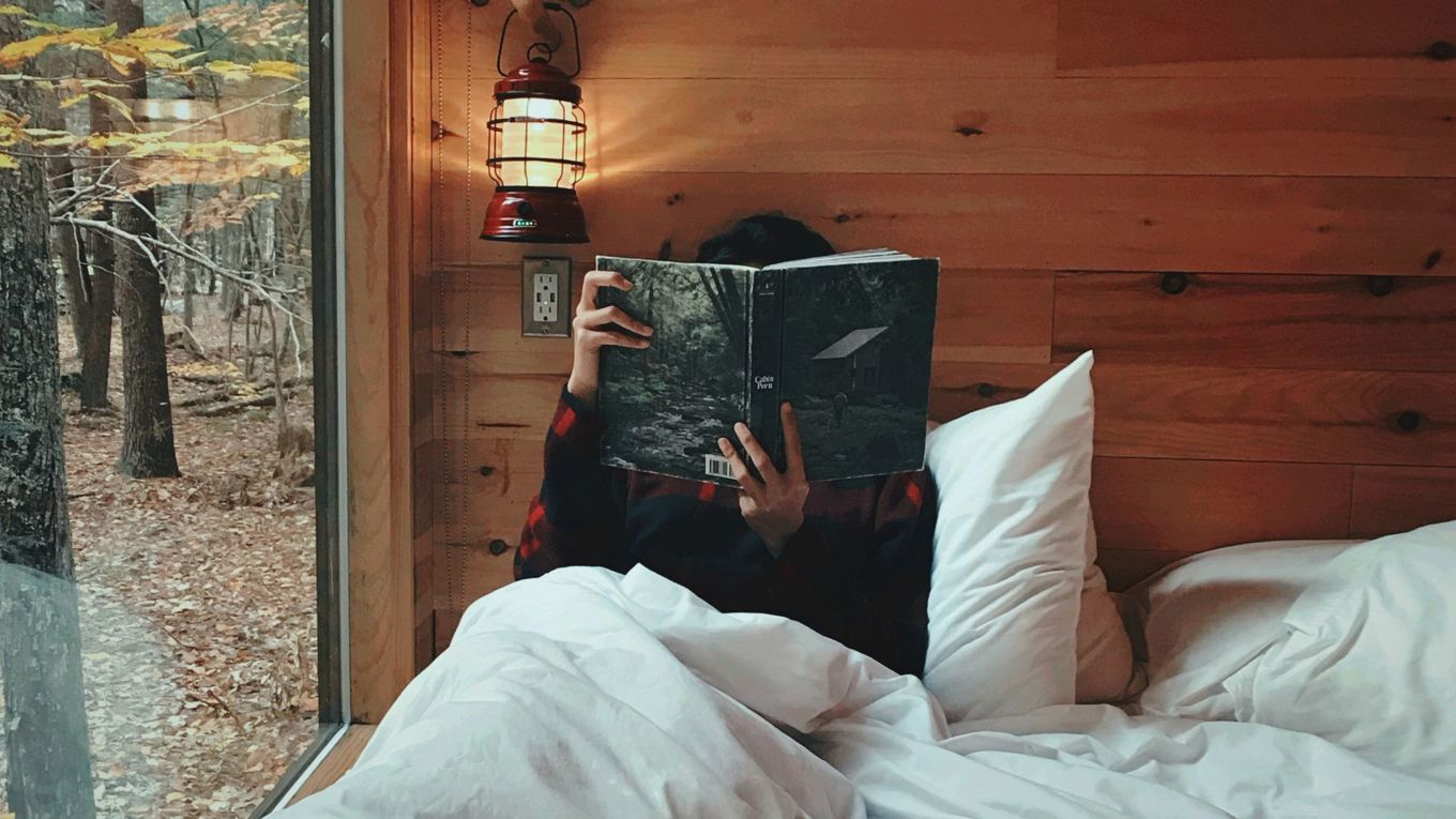 Noen som leser en bok på senga på hytta