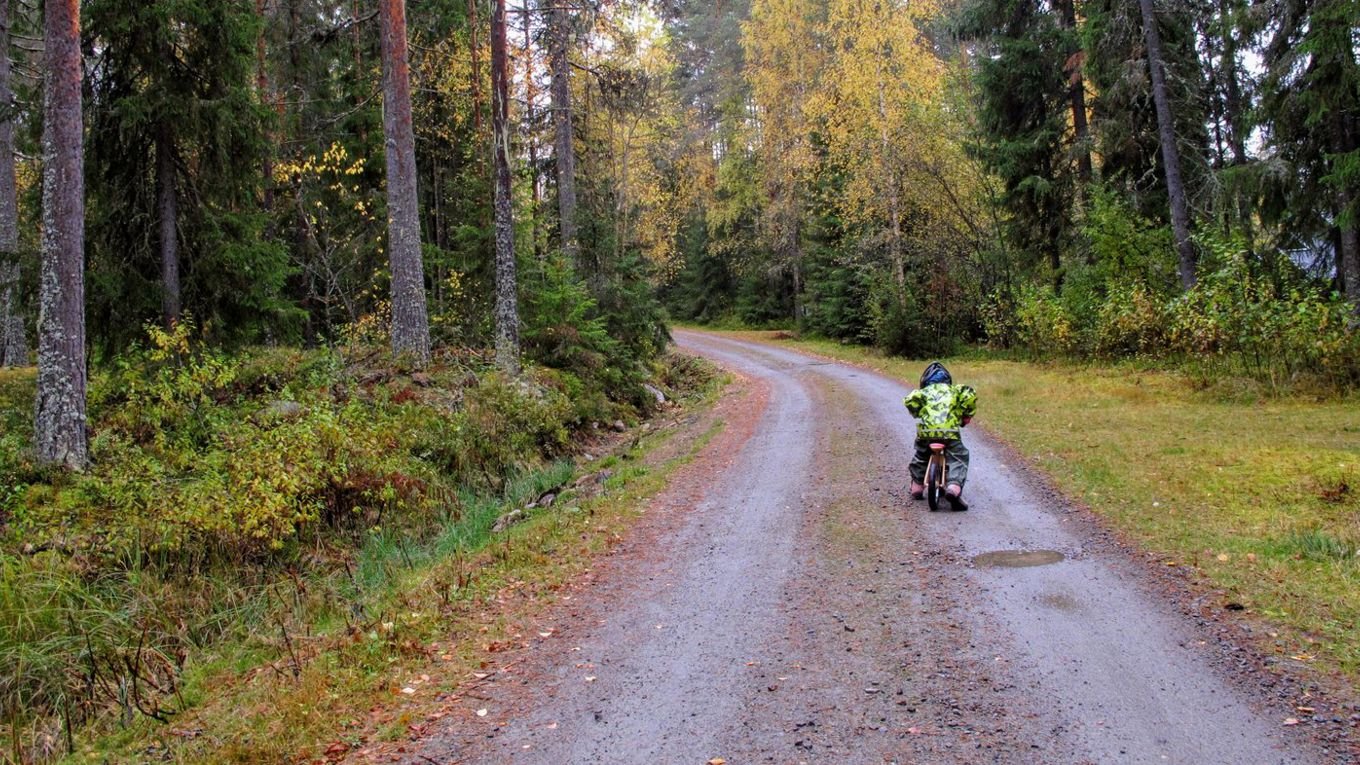 Et barn sykler langs en vei i skogen