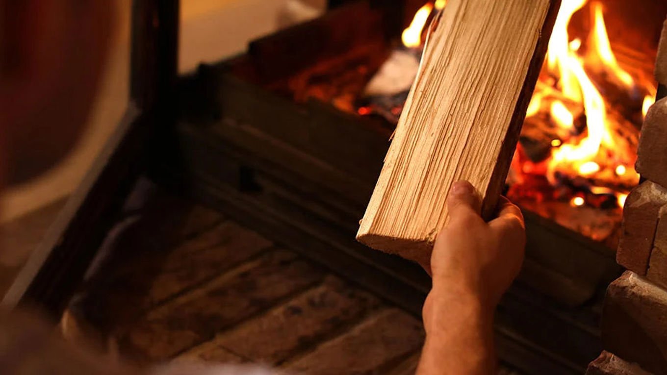 En vedkubbe legges inn i peisen